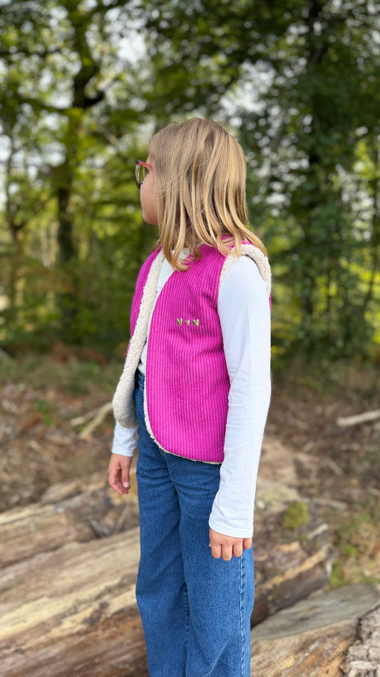 Petite fille portant un gilet sans manche enfant en velours côtelé aubergine, en extérieur