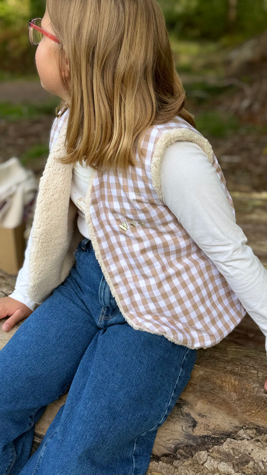 Petite fille portant un gilet sans manche enfant en vichy beige doublé sherpa