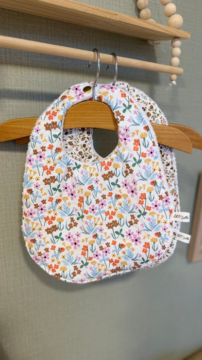 Bavoir bébé Lunelle à fleurs multicolores roses, bleues et orange sur fond blanc