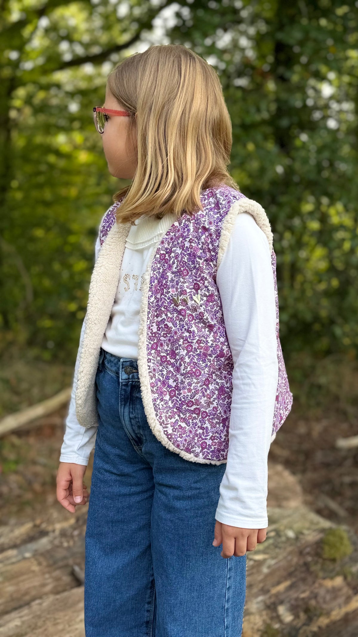 Petite fille portant un gilet sans manche enfant fleuri mauve doublé sherpa, en extérieur