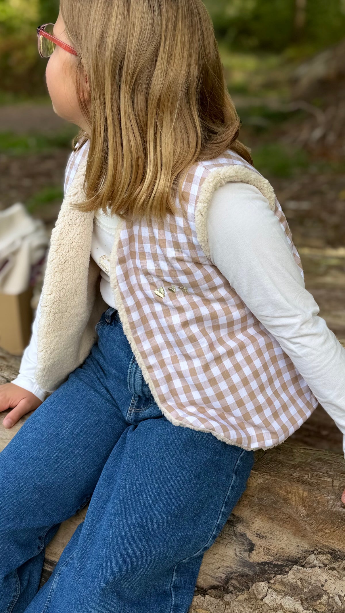 Petite fille portant un gilet sans manche enfant en vichy beige doublé sherpa