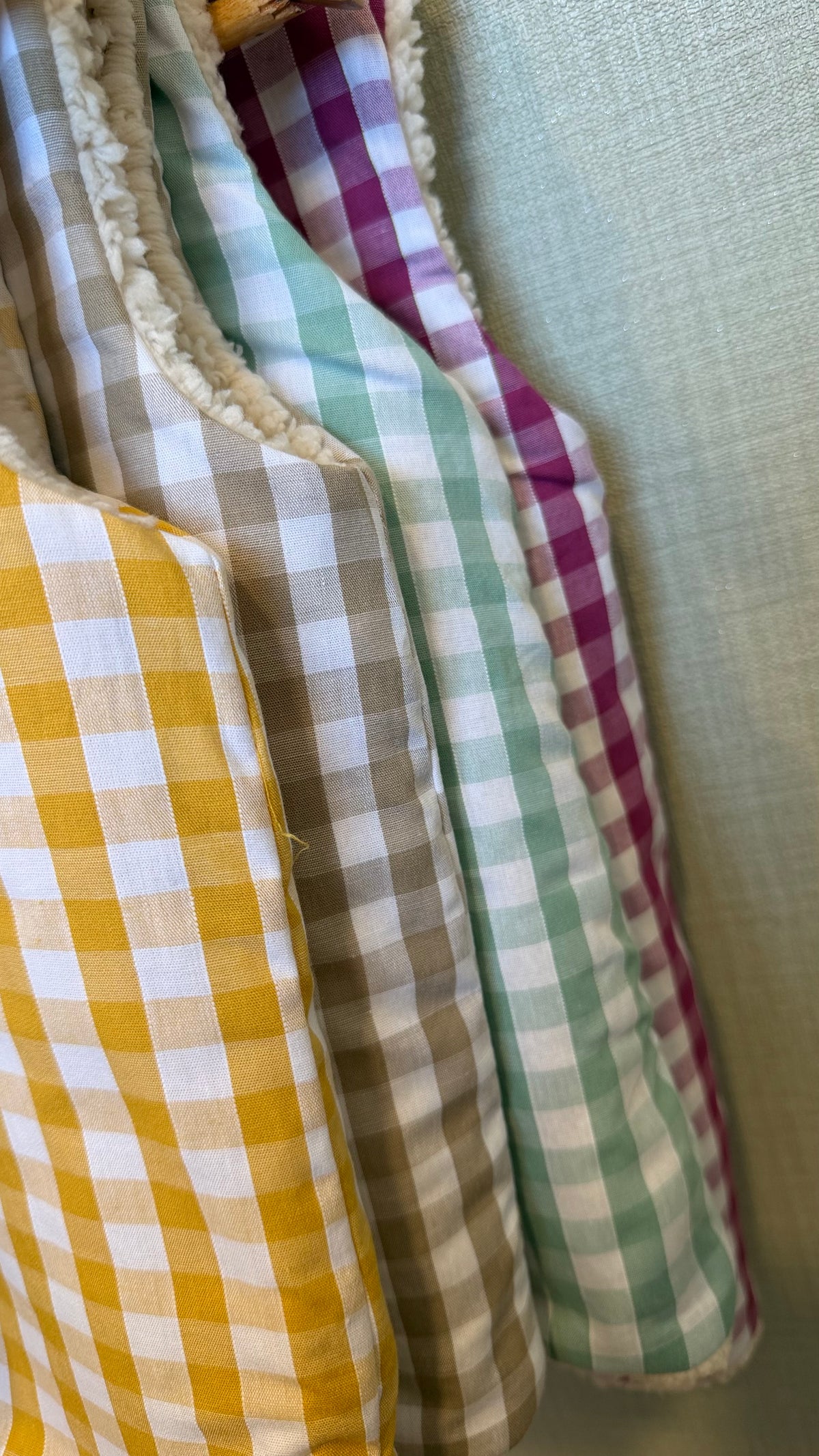 Détail des coloris vichy moutarde, beige, sauge et prune des gilets sans manche enfant