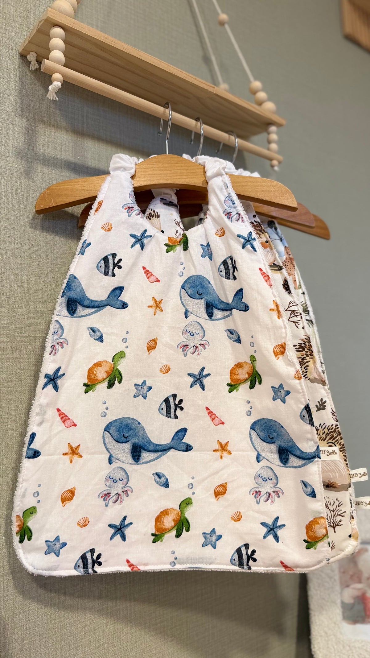 Grand bavoir maternelle Zouzou motif baleines, tortues et animaux marins sur fond blanc