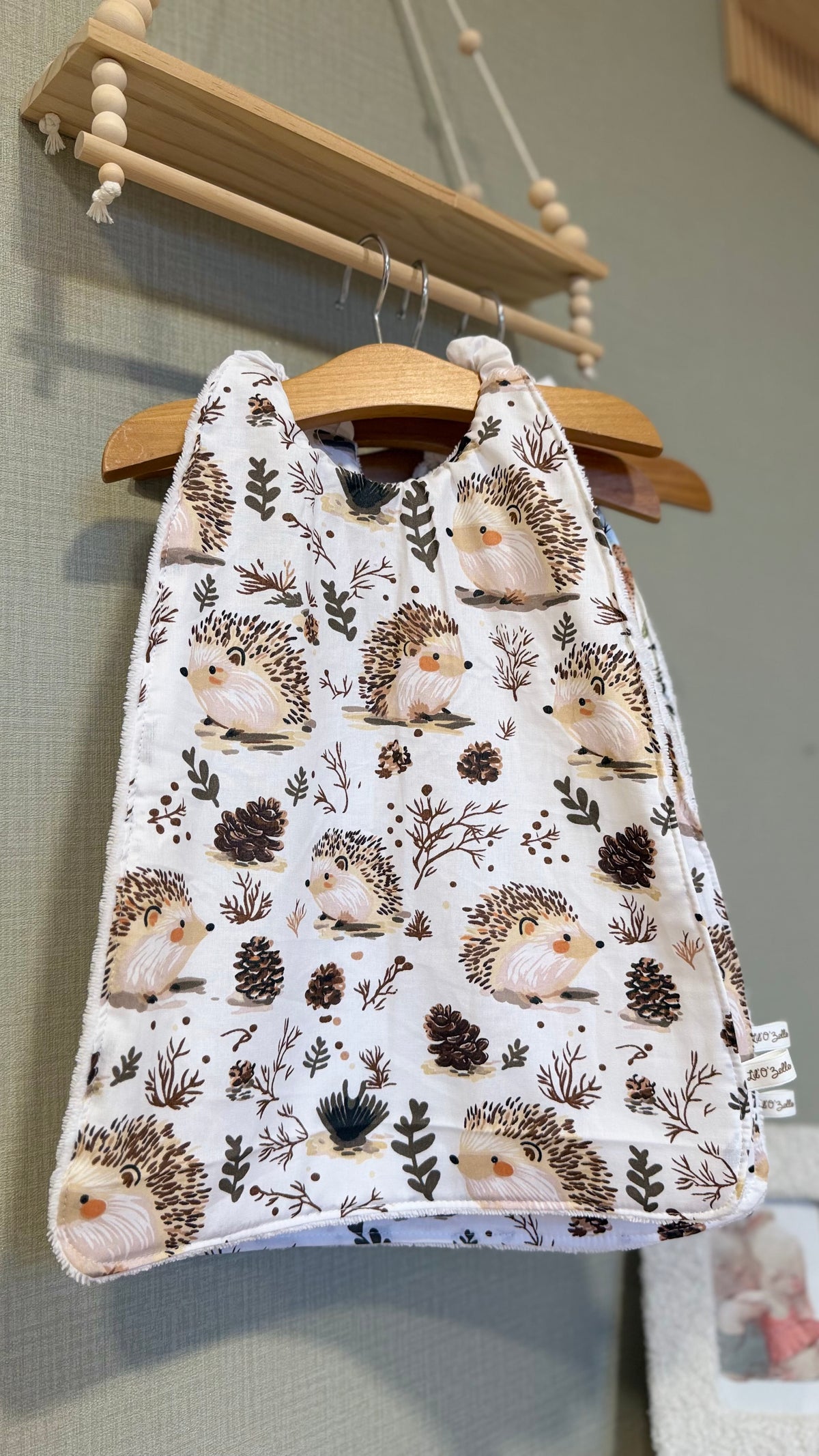 Grand bavoir maternelle Zouzou motif hérissons et pommes de pin sur fond blanc
