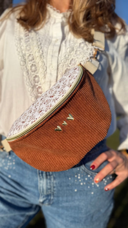 Sac banane Lovia en velours côtelé camel, rabat fleuri et cœurs dorés brodés, porté à la taille