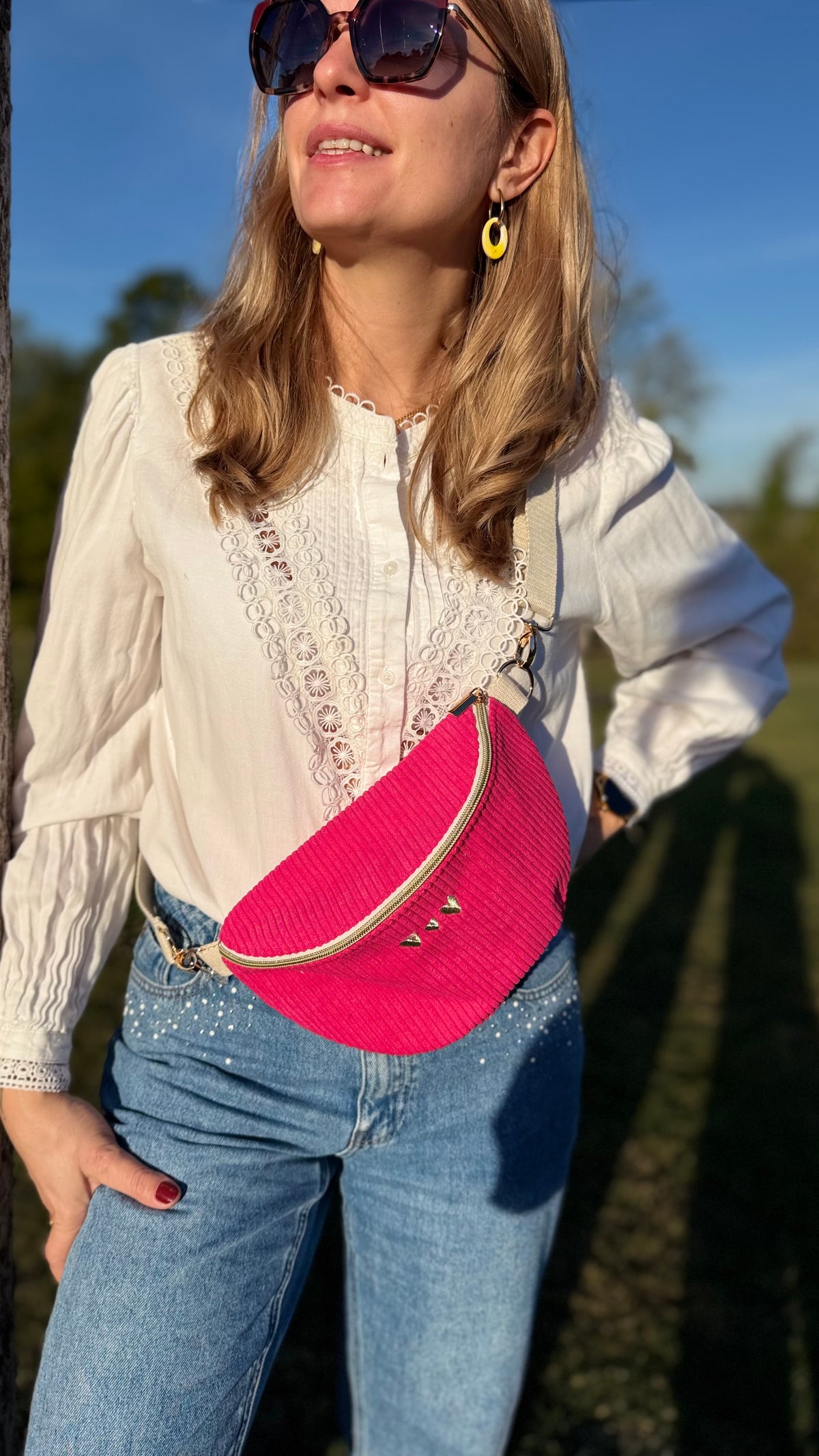 Femme portant le sac banane Lovia en velours côtelé fuchsia en bandoulière, en extérieur