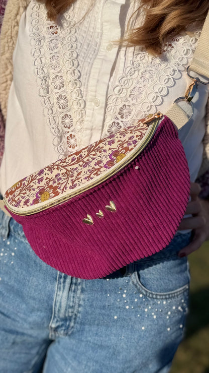 Sac banane Lovia en velours côtelé prune, rabat fleuri et trois cœurs dorés brodés, porté en bandoulière